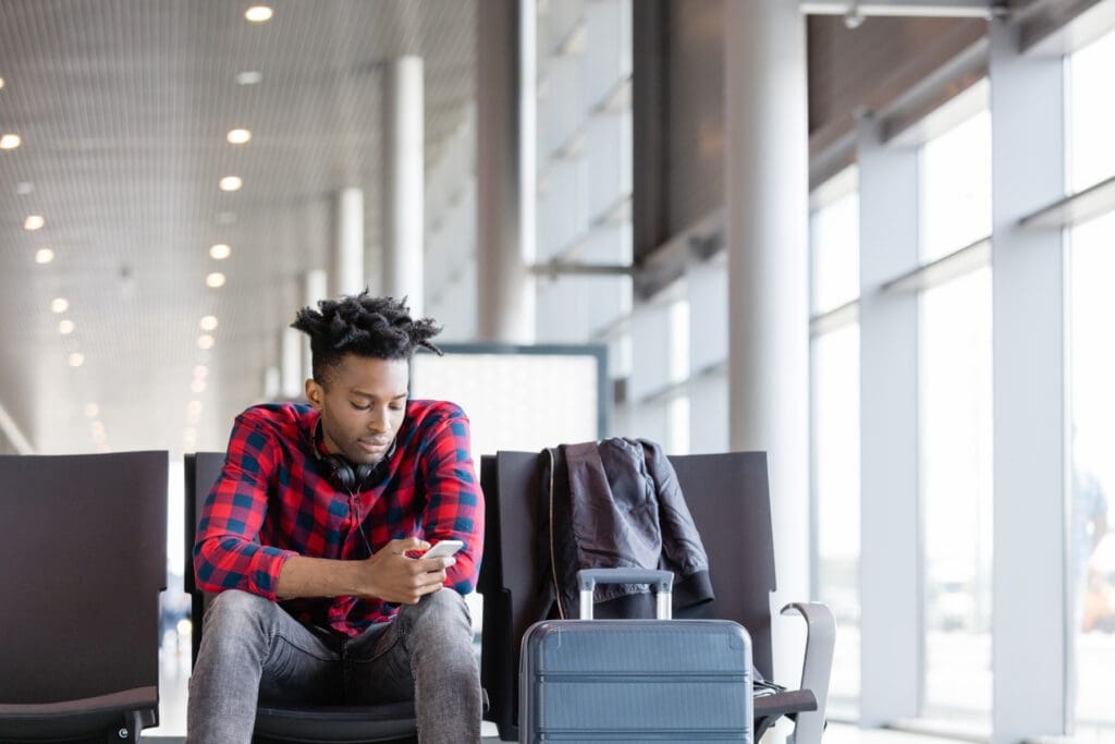 Traveler checking information on a phone while waiting at an airport