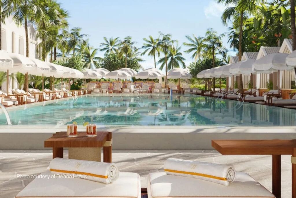 Pool at Delano Miami Beach surrounded by palm trees, white umbrellas, and poolside cabanas