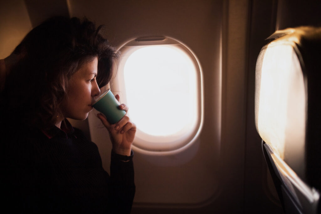 Woman drinking water during a flight, illustrating how to stay hydrated while flying