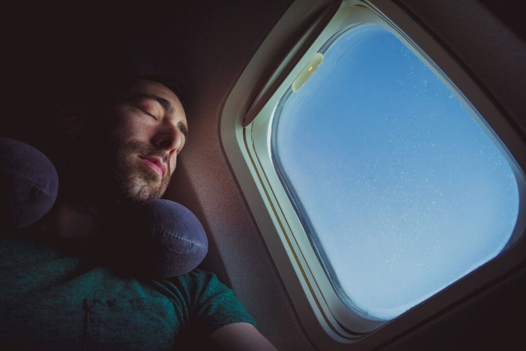 Traveler sleeping comfortably on a long-haul flight with a neck pillow