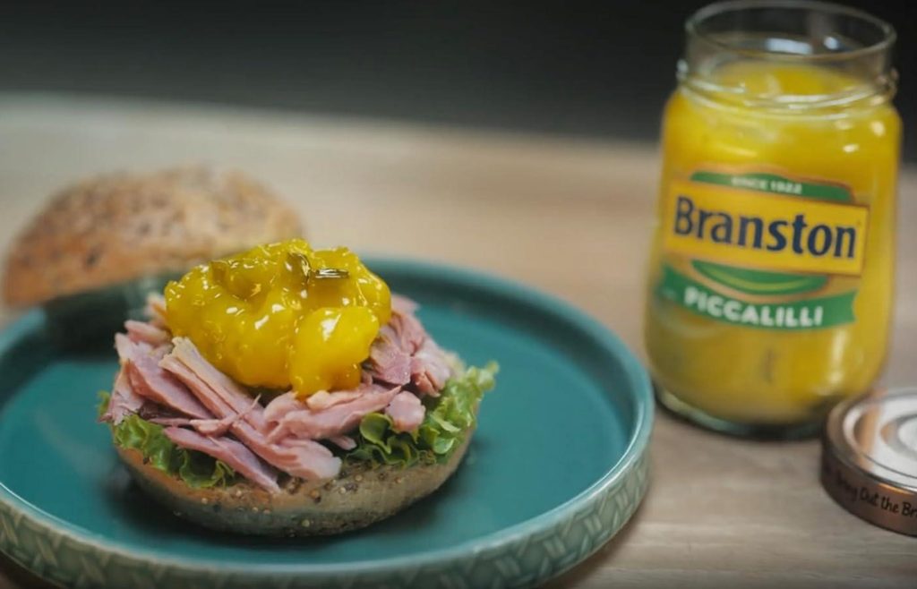 Jar of Branston piccalilli beside a sandwich