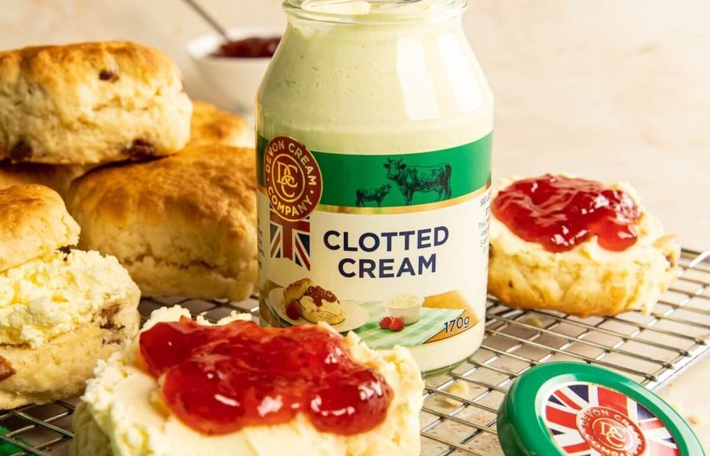 Jar of clotted cream with scones and strawberry jam