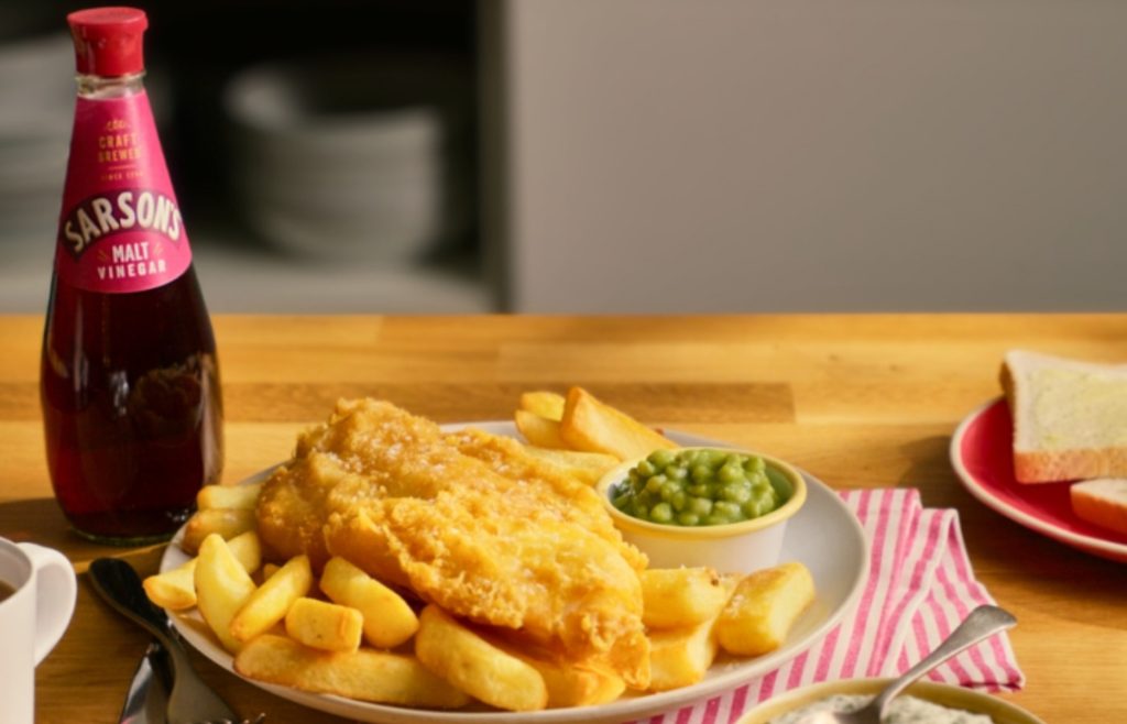 Bottle of Sarson’s malt vinegar beside fish and chips